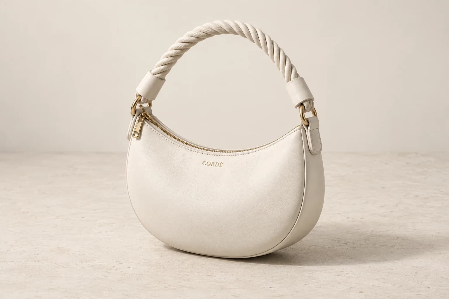 Visualização conceitual da Shoulder Bag off-white em couro napa, com alça de corda náutica e ferragens douradas, vista frontal em perspectiva